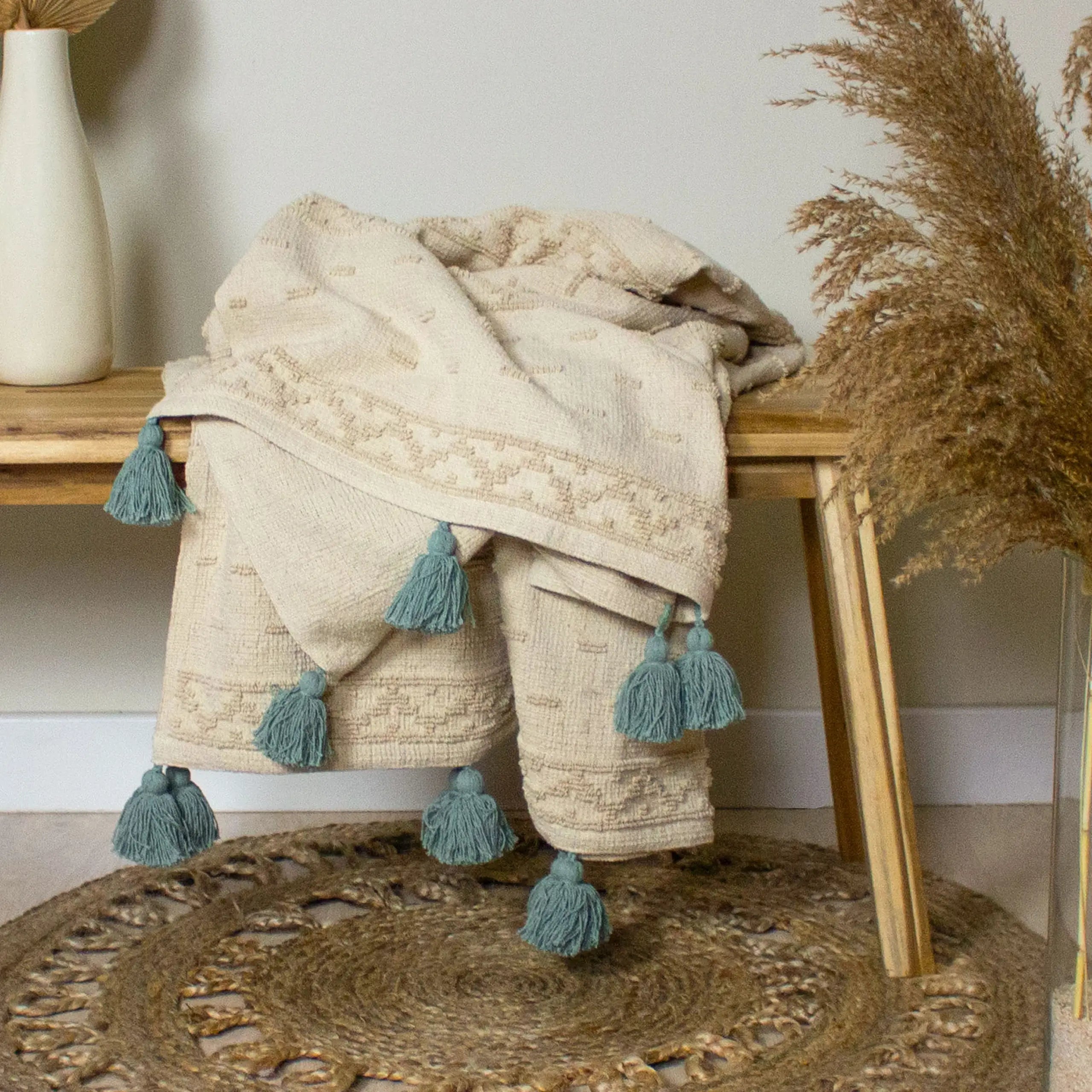 A tufted cotton throw folded over a round jute rug